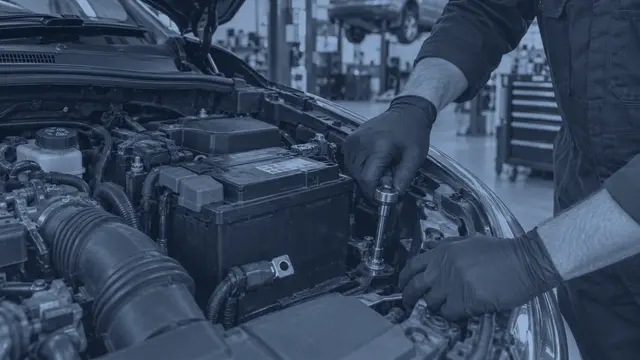A car battery being fitted under the bonnet in our workshop