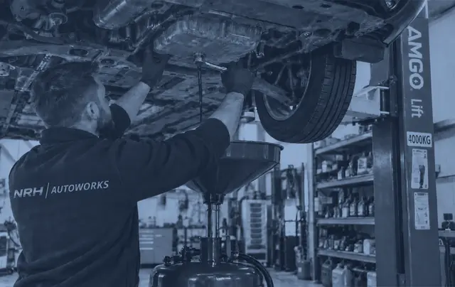 Engine oil being drained from a car on the lift during a service in our workshop