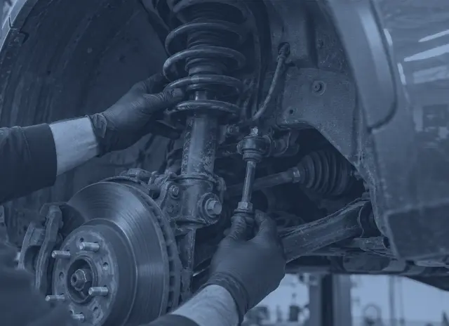 A mechanic checking a suspension strut, coil spring and drop link with the wheel removed