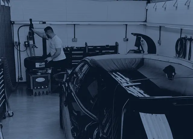 A new tyre being fitted on the tyre changer in our workshop, with a customer car in the bay