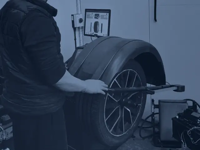 A wheel and tyre being balanced on the wheel balancer in our workshop, with the balancer screen showing